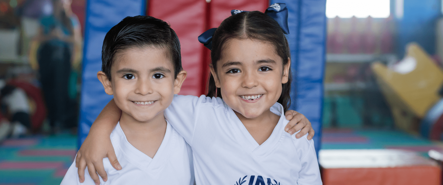 Dos alumnos de Kínder abrazados y sonriendo en el salón de juegos